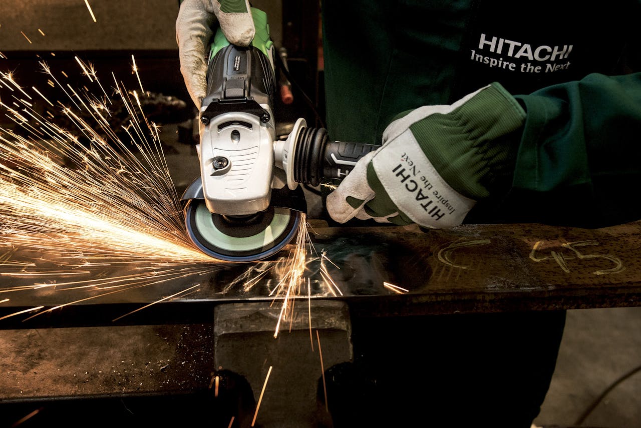 services-02 Close-up of a skilled worker using a grinder with sparks flying in a metal workshop.